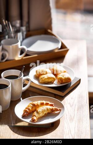 Französische Croissants mit schwarzem Kaffee auf dem Tisch im Hotelzimmer zum Frühstück Stockfoto