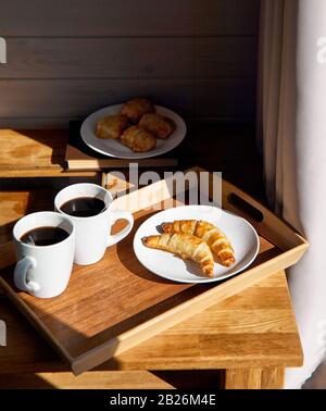 Französische Croissants, Pasteten und schwarzer Kaffee auf dem Tisch im Hotelzimmer zum Frühstück Stockfoto
