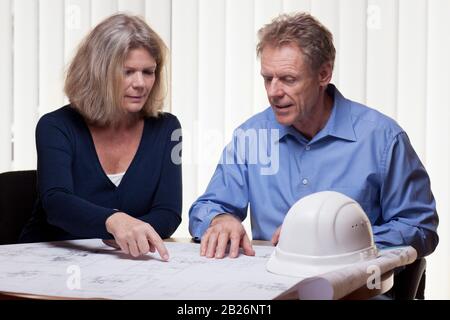 Zwei Architekten oder Ingenieure, die Details einer Blaupause in einem hellen Büro diskutieren Stockfoto