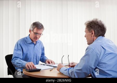 Der Berater berechnet in einem weißen Büro mit dem Kunden im Vordergrund Stockfoto