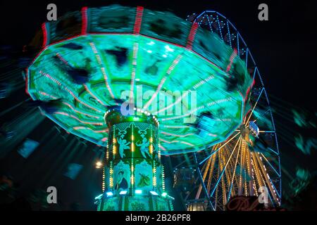 Bewegen Sie das verschwommene Karussell bei Nacht mit dem Riesenrad im Hintergrund Stockfoto