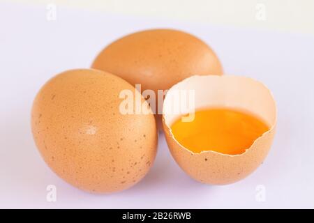 Drei braune Eier mit einem sind isoliert auf weißem Grund gebrochen Stockfoto