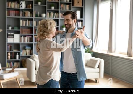 Seniormutter und erwachsener Sohn tanzen zu Hause Stockfoto