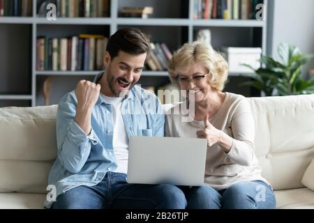 Überfreudiger junger Mann und ältere Mutter entspannen sich gemeinsam zu Hause Stockfoto