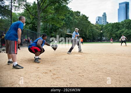 Softballspiel auf Heckscher Ballfields mit Senior man, Central Park, NYC Stockfoto