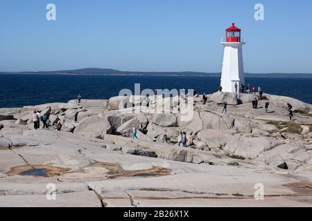 Peggy's Cove, Nova Scotia, ruhiger Leuchtturm auf Felsen mit Touristen, die an Land gehen Stockfoto