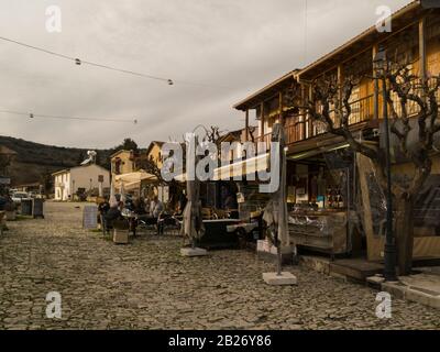 Besucher, die vor einem Restaurant im attraktiven historischen Dorf Omodos Zypern in den Troodos-Bergen sitzen, haben die Demetri Liperti Straße gepflastert Stockfoto