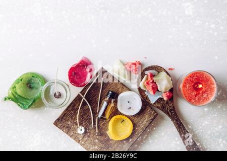 Alte Kerzen wiederverwenden und Schmelzen zu einem neuen: Verschiedene Zutaten auf dem Tisch: Kerzenwicke, Glasbecher, alte Kerzen Wachs, Aromaöl. Top vie Stockfoto