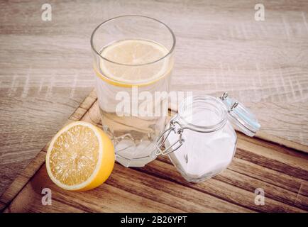 Natron im Trinkglas mit Wasser und Zitronensaft, gesundheitliche Vorteile für das Verdauungskonzept auf natürlichem Holzhintergrund. Stockfoto