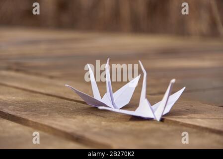 Zwei Origami-Kräne auf Holzhintergrund. Symbol für Frieden und Hoffnung. Stockfoto