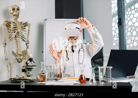 Wissenschaftler des männlichen Arztes, der eine VR-Brille trägt, die im Cyberspace arbeitet. Man in Lab coat Modellierungsergebnisse der klinischen Forschung. Zukünftige Technologien, neu Stockfoto