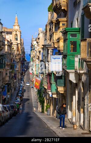 Valletta auf Malta, abschüssige Straße in der Hauptstadt, gesäumt von traditionellen maltesischen Häusern mit Balkon Stockfoto