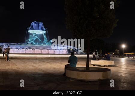 Die Menschen genießen einen ruhigen Abend am nachts beleuchteten Tritonbrunnen auf einem Platz in der Nähe der Stadt Valletta in Malta Stockfoto