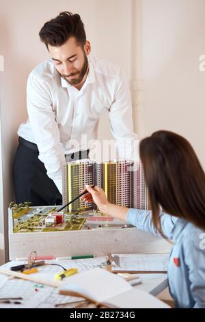 Zwei kluge Kollegen diskutieren über Bauvorhaben. Junge Männer arbeiten zusammen an einem neuen Baumodell, Nahaufnahme vertikal shot.Architectural, construt Stockfoto