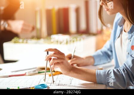 Mädchen, die ein Problem mit ihren technischen Zeichnungen haben, arbeiten im Büro. Nahansicht Foto zugeschnitten, Frau entwickelt architektonische Fähigkeiten Stockfoto