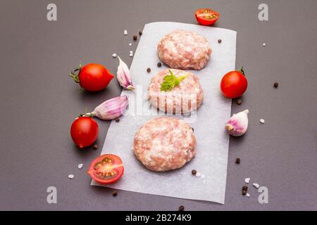 Rohe frische Schweinefleischschnitzel mit Gewürzen und Gemüse Gesundes Esskonzept, tierische Proteine und Vitamin. Auf steinernem Grund. Stockfoto