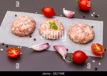 Rohe frische Schweinefleischschnitzel mit Gewürzen und Gemüse Gesundes Esskonzept, tierische Proteine und Vitamin. Auf steinernem Grund. Stockfoto