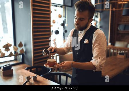 Junger Mann in Mode, der lernt, Kaffee zu machen, Nahaufnahme Foto. Stockfoto