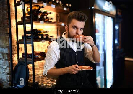 Junger talentierter professioneller Barista, der gut zubereiteten Kaffee schmeckt, Nahansicht Foto. Degustationskonzept Stockfoto