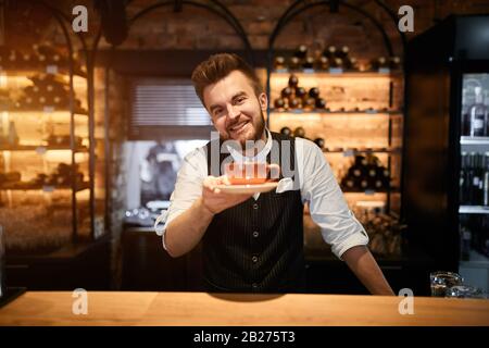 Angenehmer freundlicher Barista, der dem Kunden Kaffee gibt, hier ist Kaffee. Nehmen Sie Ihren Tee. Nahaufnahme Foto. Fantastischer Geschmack Stockfoto