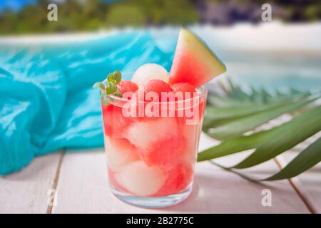 Tropischer Obstsalat mit Melone und Wassermelone Kugeln aus Glas unter dem palm leaf Stockfoto