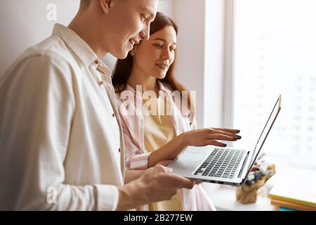 Junge Leute, die online plaudern, betäuben, Seitenansicht aus nächster Nähe Foto.Paar auf der Suche nach einer Wi-Fi-Verbindung. Seitenansicht Foto.Mann und Frau einkaufen Stockfoto