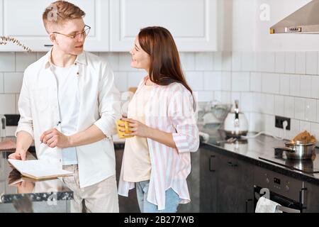 Cleverer Mann, der seinen Frau Ratschläge, Inspiration hört, gutaussehender Mann in Brillen, die einen Stift halten und sein zukünftiges Buch mit Frau diskutiert, fragt der Schriftsteller Stockfoto