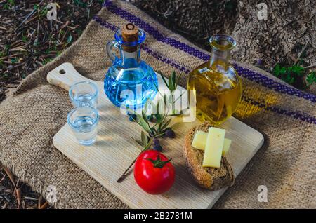 Kretische Küche mit nativem Olivenöl, Oliven, kretischem Barley Rusks, lokalem Käse und Karaffe von kretischem Raki. Stockfoto