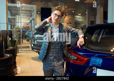 Junger gutaussehender Mann in Brille und Mode Karomuster in einem leichten Autohaus, er kauft offensichtlich ein Auto oder ist Autohändler. Shop assista Stockfoto