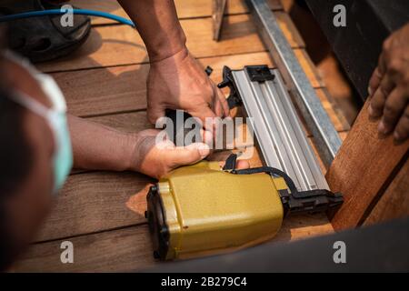 Nahaufnahme eines Tischlers mit einem Luftnagelgewehr, um Holztisch im Garten zu vervollständigen Stockfoto