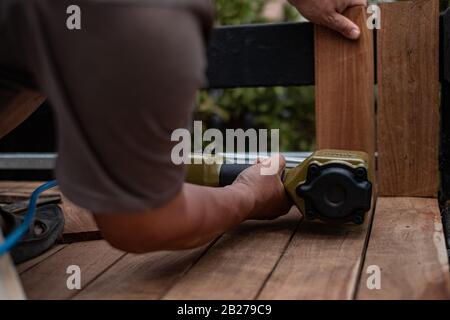 Nahaufnahme eines Tischlers mit einem Luftnagelgewehr, um Holztisch im Garten zu vervollständigen Stockfoto