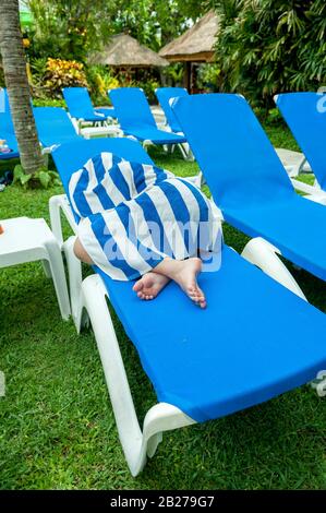 Junge Frau mit Strandtuch bedeckt, um sich vor der Sonne zu schützen. Bali, Indonesien Stockfoto