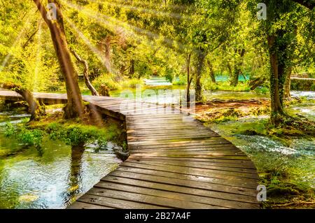 Holzsteg im grünen Wald des Krka National Park, Kroatien. Schöner Wanderweg oder Fußweg über den Fluss in der Nähe von Krka-Wasserfällen. Szene Wi Stockfoto