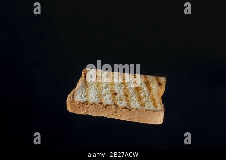Nahaufnahme der goldenen Toastschicht auf schwarzem Hintergrund Stockfoto