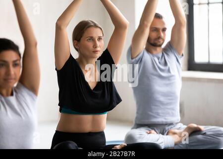 Verschiedene Menschen, die während der Yoga-Sitzung meditieren, konzentrieren sich auf kaukasische Frauen Stockfoto