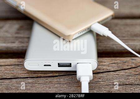 Smartphone wird mit powerbank auf der Bank aufgeladen. Stockfoto