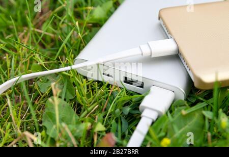 Smartphone wird mit powerbank auf dem Rasen aufgeladen. Stockfoto