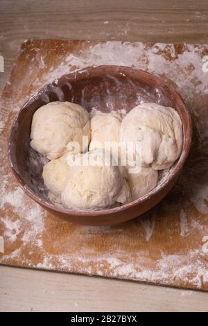 Teigkugeln. Sperrholzschneidebrett, Holzmehlsieb und Walzstift - Werkzeuge zur Herstellung von Teig. Stockfoto