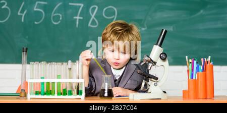 Schulbildung. Untersuchen Sie biologische Moleküle. Baby mit einem kleinen Genie. Technologie- und Wissenschaftskonzept. Junge in der Nähe von Mikroskop und Reagenzgläsern im Schulunterricht. Kid studiert Biologie und Chemie in der Schule. Stockfoto