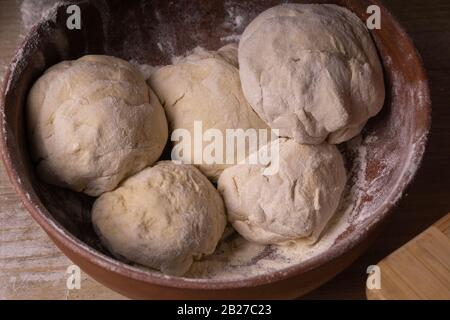 Teigkugeln. Sperrholzschneidebrett, Holzmehlsieb und Walzstift - Werkzeuge zur Herstellung von Teig. Stockfoto