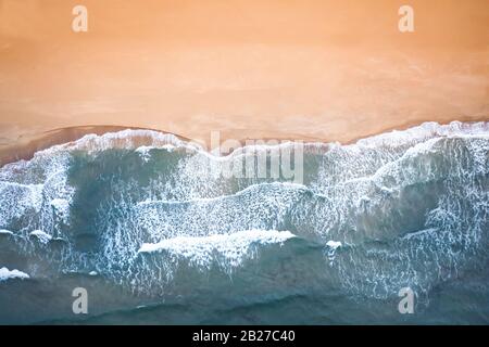 Sandstrandantenne, Draufsicht auf einen schönen Sandstrandflug mit den blauen Wellen. Stockfoto