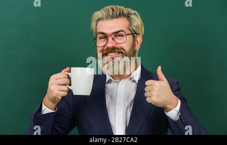Kaffeesüchtig. Energieaufladung für den ganzen Tag. Angenehmer Schluck. Kaffeepause und Entspannung. Mittagszeit für Lehrer. Koffeindosis. Optimistisches Konzept. Lehrer in der Brille trinken Kaffee Kelkboard Hintergrund. Stockfoto
