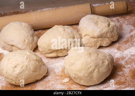 Teigkugeln. Sperrholzschneidebrett, Holzmehlsieb und Walzstift - Werkzeuge zur Herstellung von Teig. Stockfoto