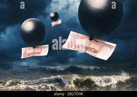 Hundert Yuan im Ballon vor dem Hintergrund stürmischer Wellen und stürmischer Himmel. Das Konzept zum Thema Fall der chinesischen Währung Stockfoto