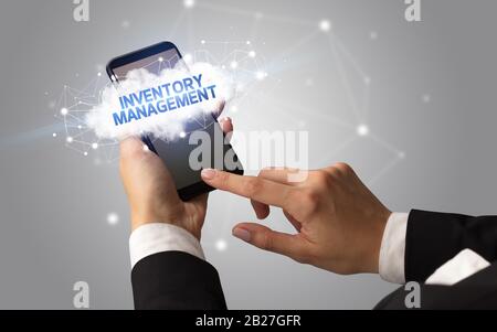 Weibliche Hand berühren Smartphone mit Inventory Management Inschrift, Cloud Business Konzept Stockfoto