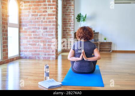 Mittelalter schöne Sportfrau auf der Matte auf der Rückansicht, die Yoga praktiziert, die umgekehrte Gebetspose im Fitnessstudio macht Stockfoto