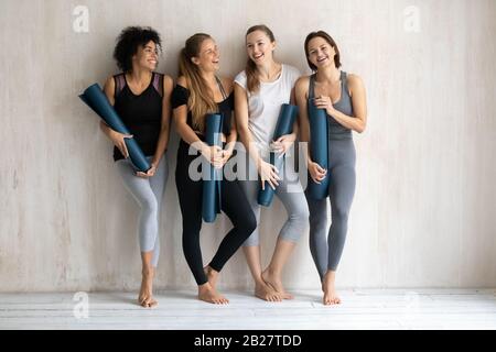 Multikulturelle Frauen tragen Sportswear und halten Yogamatten bereit für das Training Stockfoto