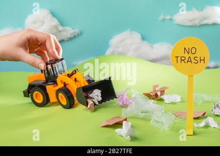 Kinder, die mit einem Spielzeug-Truck spielen, der Müll vom Rasen sammelt Stockfoto