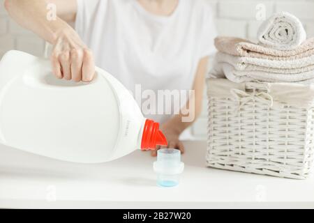 Frau will Waschmittel in die Kappe auf dem Tisch gießen, aber die Flasche ist leer, das Gel ist zu Ende, Nahaufnahme. Wäschekonzept Stockfoto