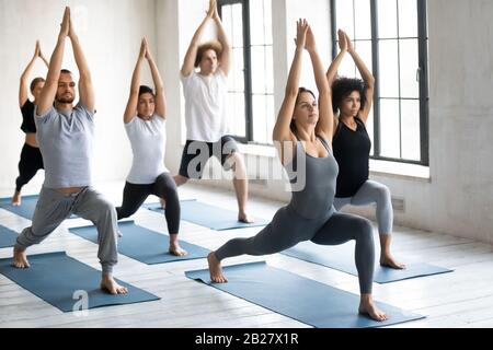 Junge Leute, die Yoga praktizieren, um Krieger eine Übung zu machen Stockfoto